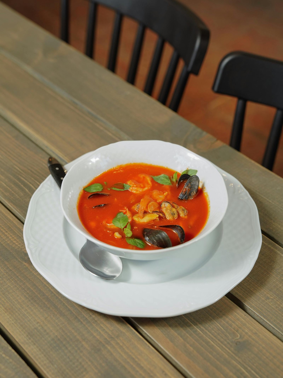 Bol blanc de bouillabaisse façon Pointu, moules, soupe rouge, basilic