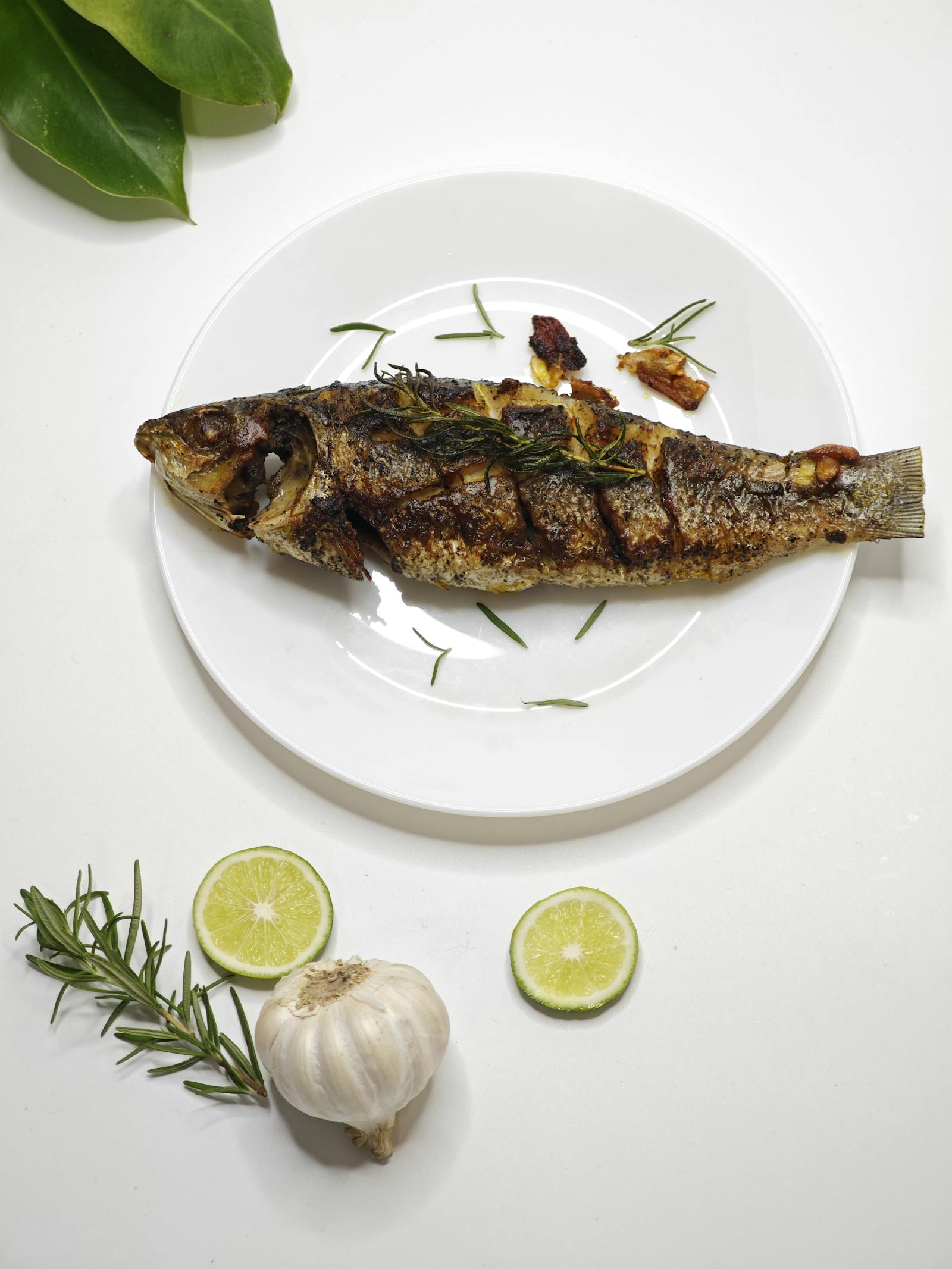 Loup entier grillé à la peau avec citron, romarin et ail