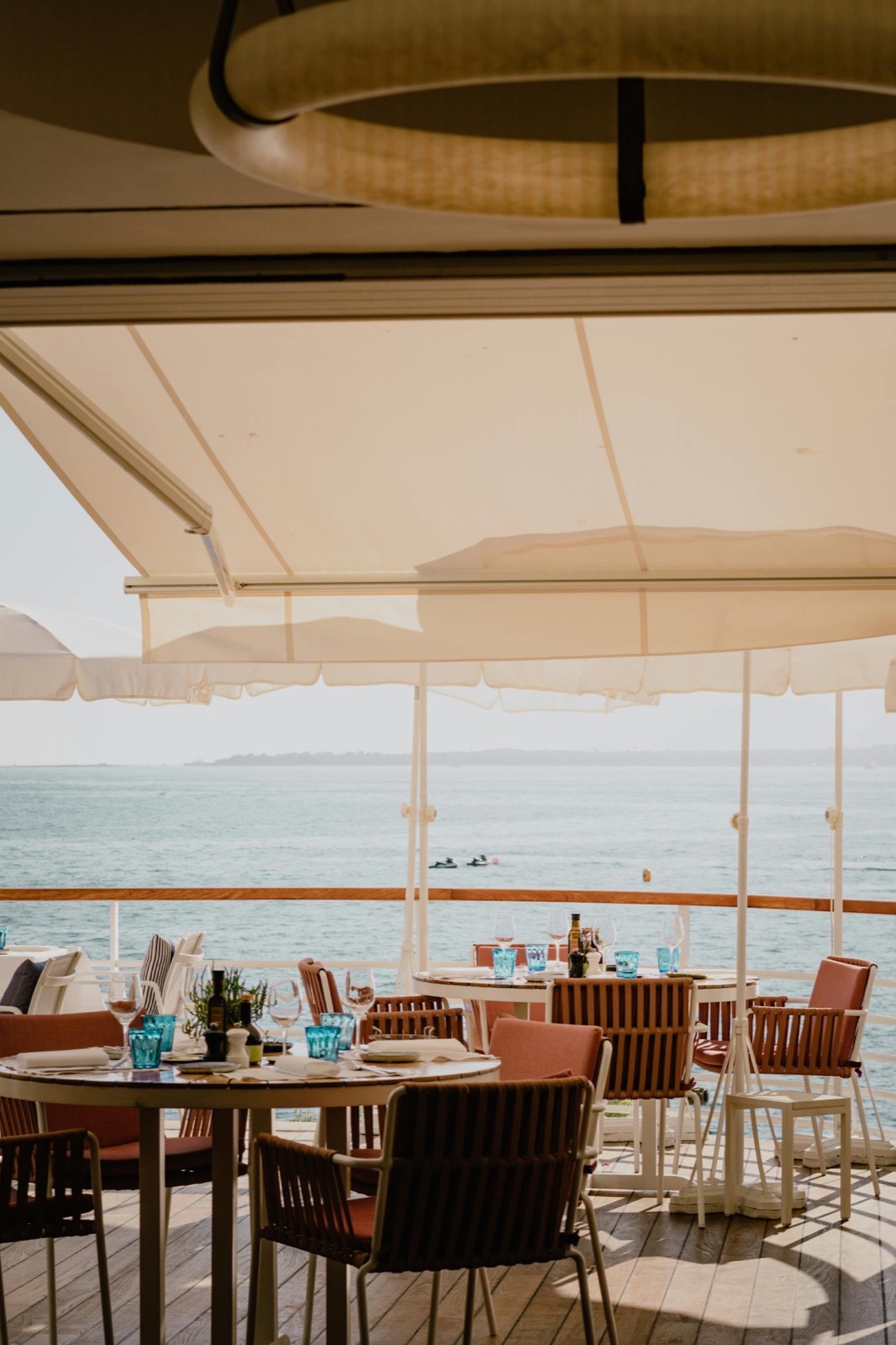 Terrasse couverte au bord de l'eau, tables dressées face à la Méditerranée